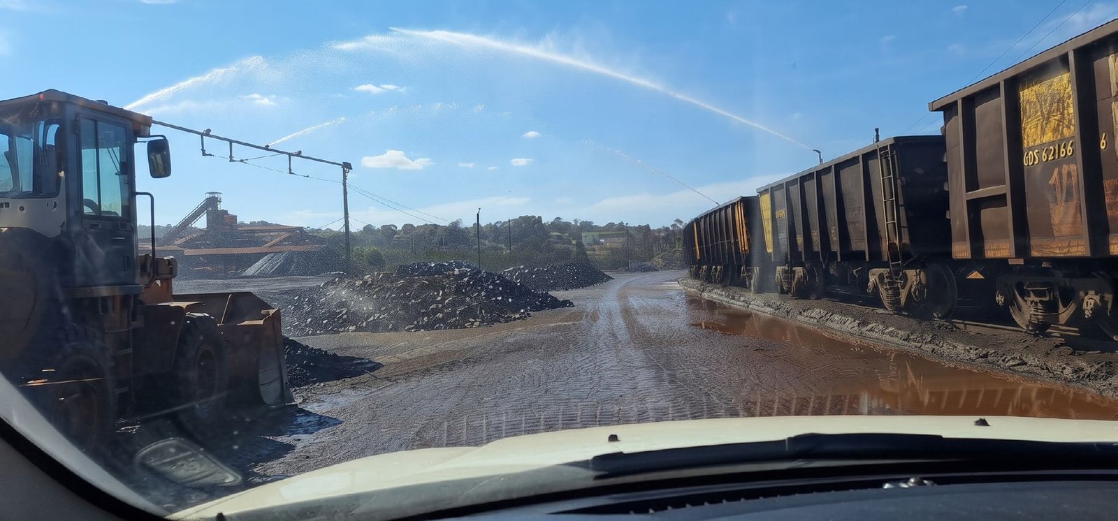 Canhão de alta pressão lançando água sobre o pátio, ao lado de vagões